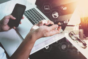 businessman working with smart phone and laptop computer on wooden desk in modern office with virtual icons interface
